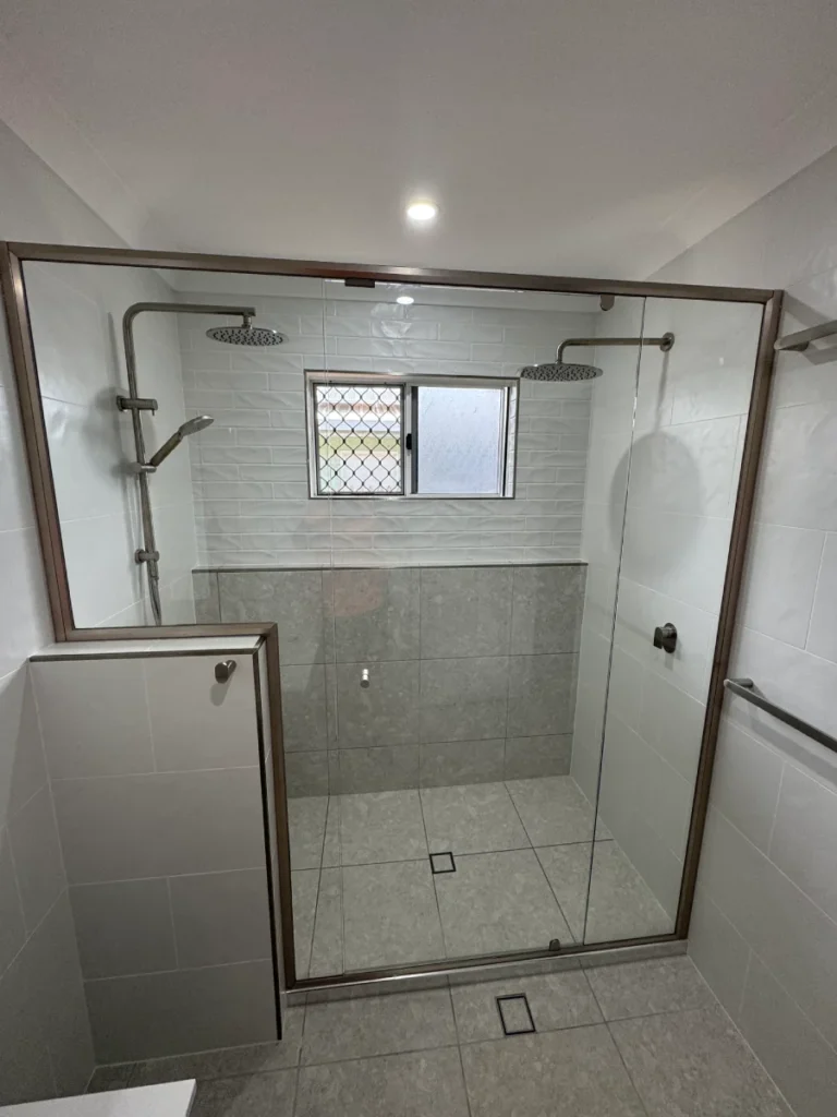 Timeless floor to ceiling white tiles, dual shower heads, finished in brushed nickel